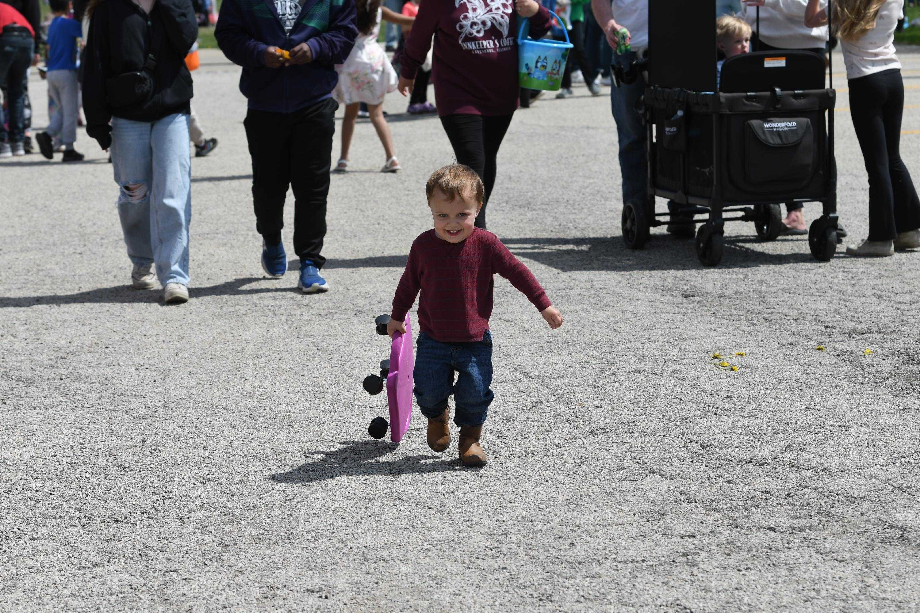 toddler walking while holding a scooer